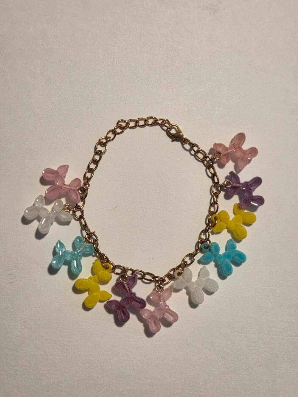 Multicolored fuzzy balloon dog pendants on a gold-tone chain bracelet